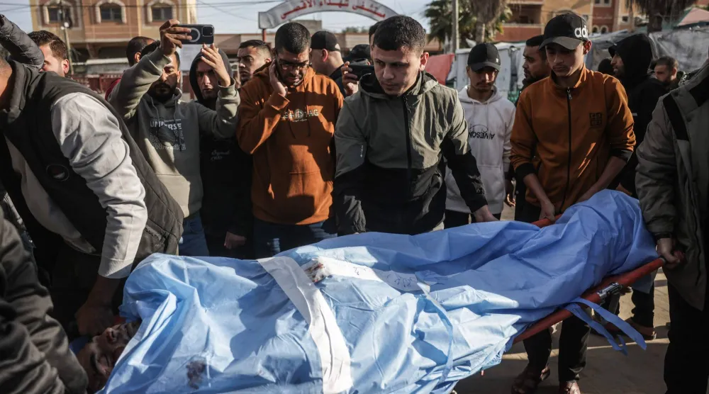 أصدقاء وأقارب للفلسطيني الراحل محمد الجرو يحملون جثمانه خلال جنازته داخل دير البلح يوم 9 ديسمبر 2025 بعد استشهاده في غارة جوية إسرائيلية (أ.ف.ب)