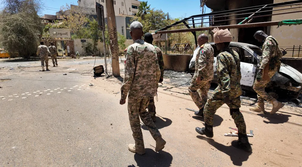 أفراد من الجيش السوداني يسيرون بجوار مركبات عسكرية مدمرة في العاصمة السودانية الخرطوم (رويترز - أرشيفية)