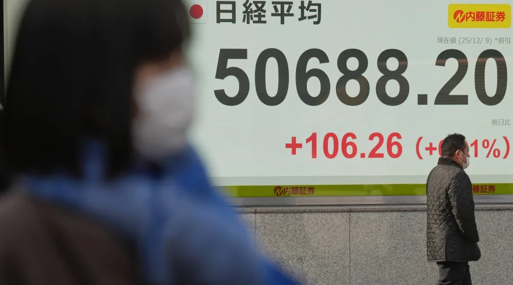 مشاة يسيرون أمام لوحة تعرض حركة الأسهم في وسط العاصمة اليابانية طوكيو (أ.ب)