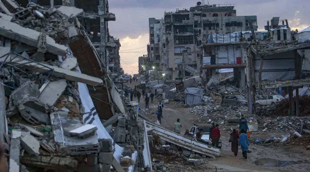 Gazze şehrinin Şeyh Rıdvan mahallesinde yıkılmış binaların arasında yürüyen yerlerinden edilmiş Filistinliler (EPA)