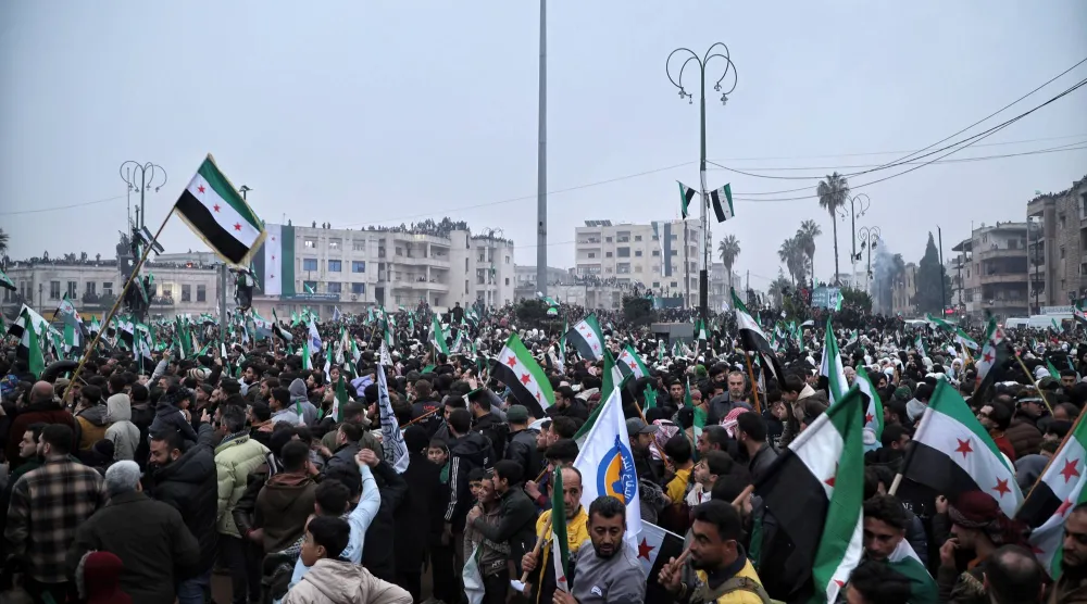 تجمع الناس خلال مسيرة إحياءً للذكرى السنوية الأولى للإطاحة بنظام بشار الأسد في إدلب (إ.ب.أ)