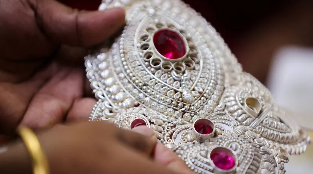 صائغ ذهب يُدخل حجراً كريماً داخل تاج فضي في ورشة لصناعة المجوهرات في مومباي بالهند (رويترز)