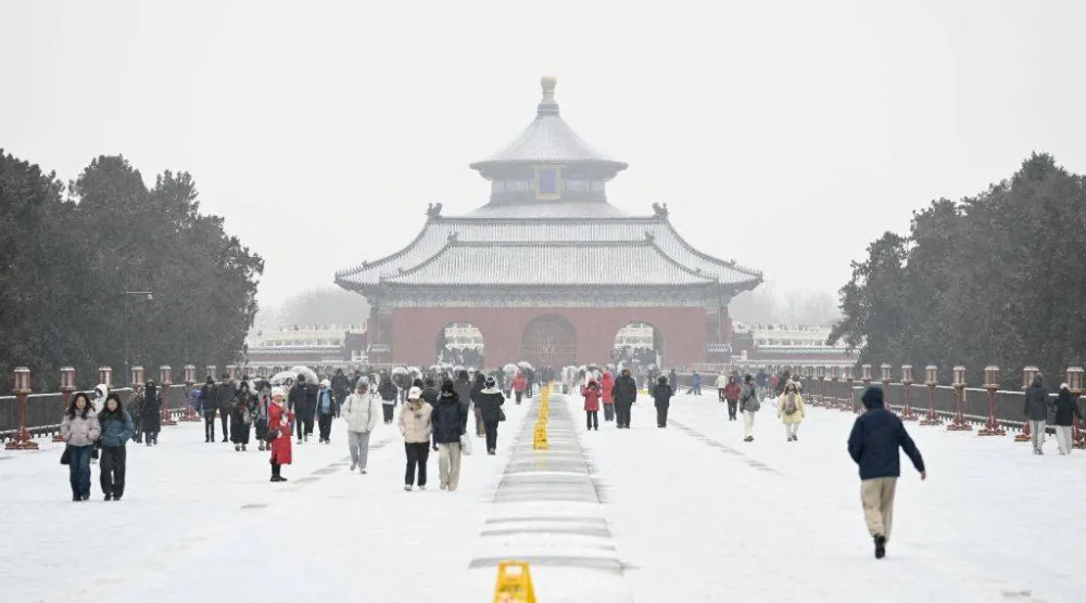 صينيون وسط الثلوج بأحد المزارات الدينية القديمة في بكين (أ.ف.ب)