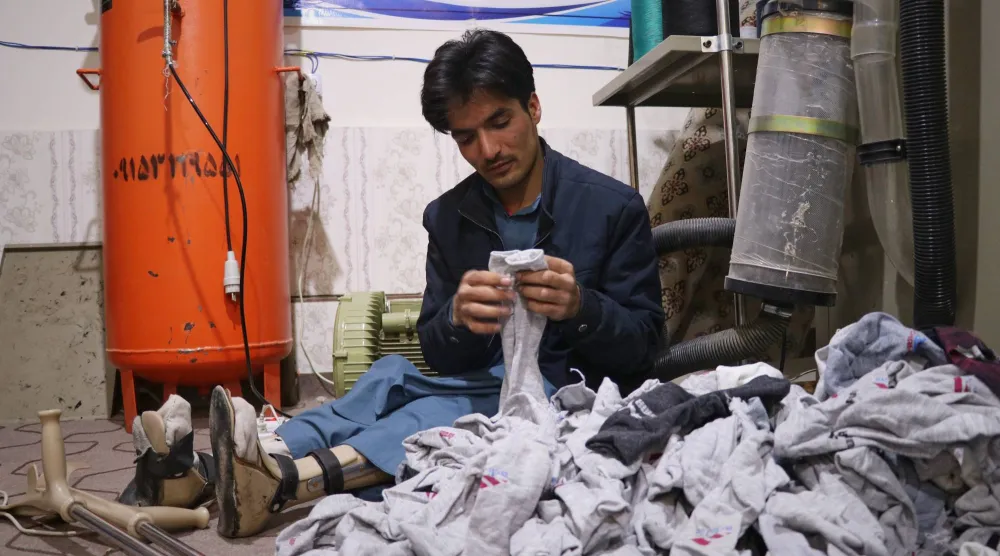 مسعود خان يقوم بفرز الجوارب المصنوعة حديثاً تمهيداً لتعبئتها في ورشة عمل للجوارب يعمل بها بالكامل رجالٌ من ذوي الإعاقة في مدينة هرات غرب أفغانستان يوم الاثنين 8 ديسمبر 2025 (أ.ب)