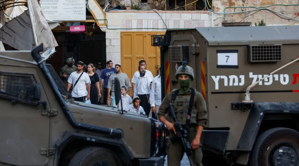 جندي إسرائيلي يقف لحماية المشاركين في جولة أسبوعية للمستوطنين في الخليل بالضفة الغربية المحتلة (أرشيفية - رويترز)