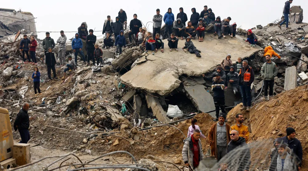 فلسطينيون خلال البحث عن ضحايا تحت أنقاض منزل انهار تحت المطر الغزير في بيت لاهيا شمال قطاع غزة الجمعة (رويترز)