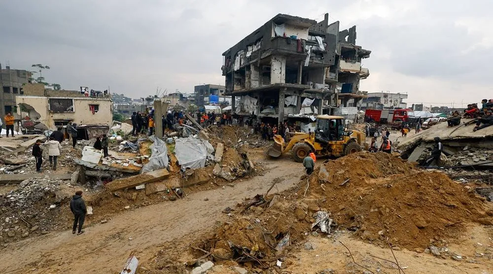 Heavy machinery operates as Palestinians gather amid a search for victims in a destroyed house that collapsed due to heavy rains, in Beit Lahia, in the northern Gaza Strip, December 12, 2025. (Reuters) 