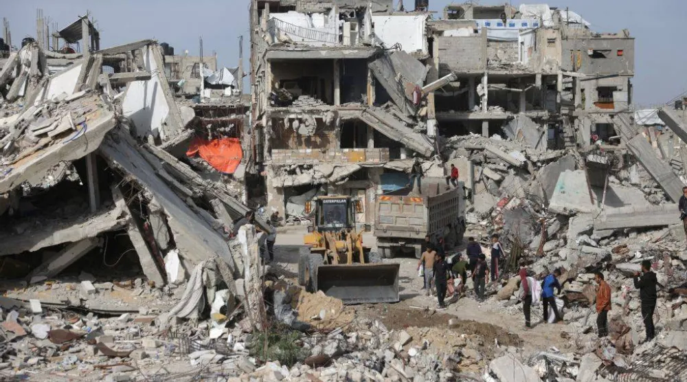 العمل على رفع أنقاض مبانٍ دمرها القصف الإسرائيلي لإعادة فتح شارع في خان يونس جنوب قطاع غزة السبت (أ.ف.ب)