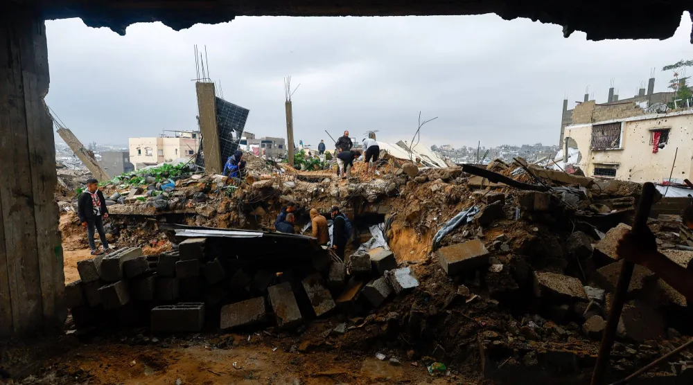 فلسطينيون يبحثون عن ضحايا جراء انهيار منزل متضرر من القصف الإسرائيلي على قطاع غزة (رويترز) 