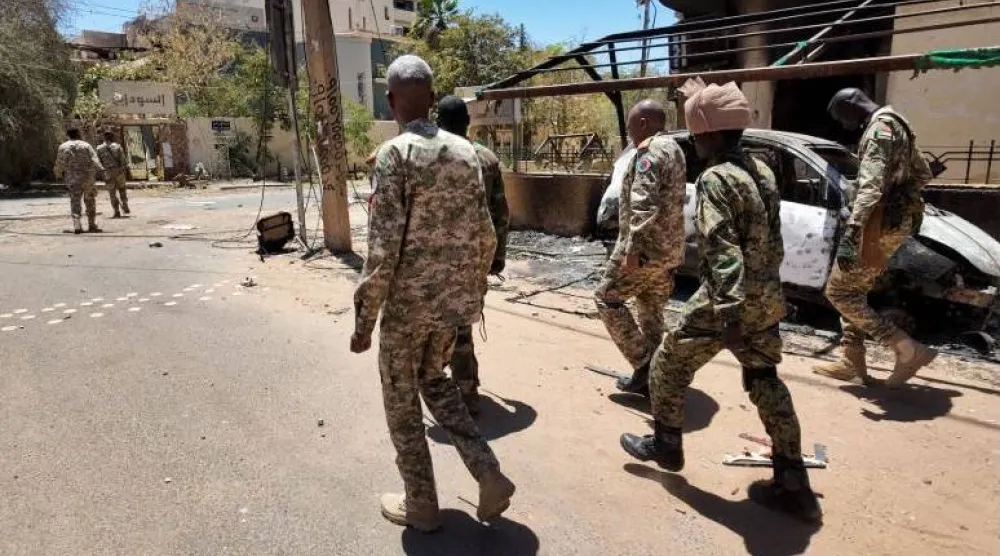 جنود من الجيش السوداني يسيرون بجوار مركبات عسكرية مدمرة بعد معركة مع «قوات الدعم السريع» في الخرطوم (رويترز)