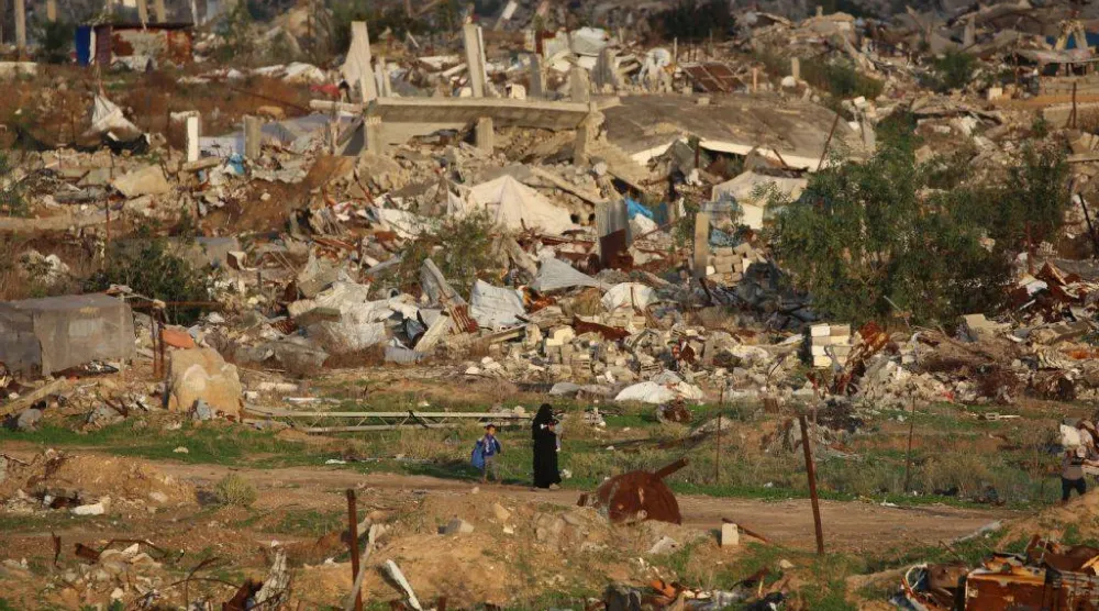 امرأة فلسطينية تمر عبر الدمار الناتج عن الحرب في مخيم النصيرات بوسط قطاع غزة (أ.ف.ب)