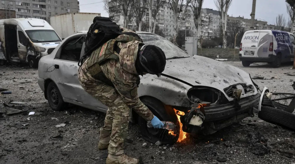 ضابط شرطة يُطفئ سيارة محترقة في موقع غارة جوية روسية بطائرة مسيَّرة وسط الهجوم على أوكرانيا في زابوروجيا (رويترز)