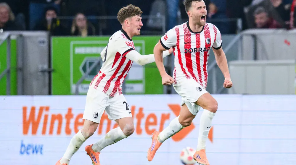 Freiburg's Lucas Hoeler, right, celebrates after scoring his side's first goal during the German Bundesliga soccer match between SC Freiburg and Borussia Dortmund in Freiburg, Germany, Sunday, Dec. 14, 2025. (Tom Weller/dpa via AP)