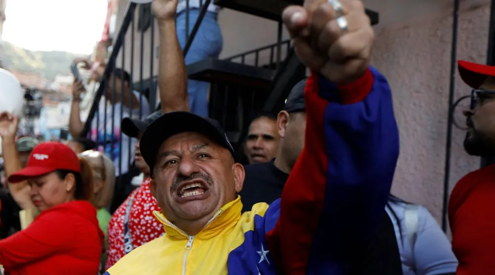 أحد مؤيدي الحكومة يلوّح بيده خلال احتجاج على احتجاز الولايات المتحدة ناقلة نفط فنزويلية في كاراكاس (رويترز)