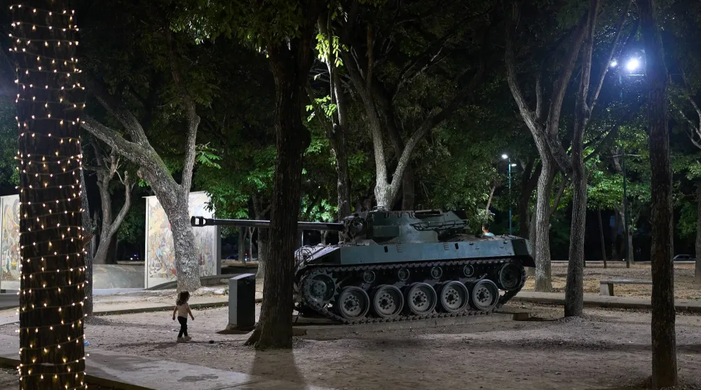 طفل يمر قرب مصفحة معروضة في كاراكاس بفنزويلا (أ.ب)