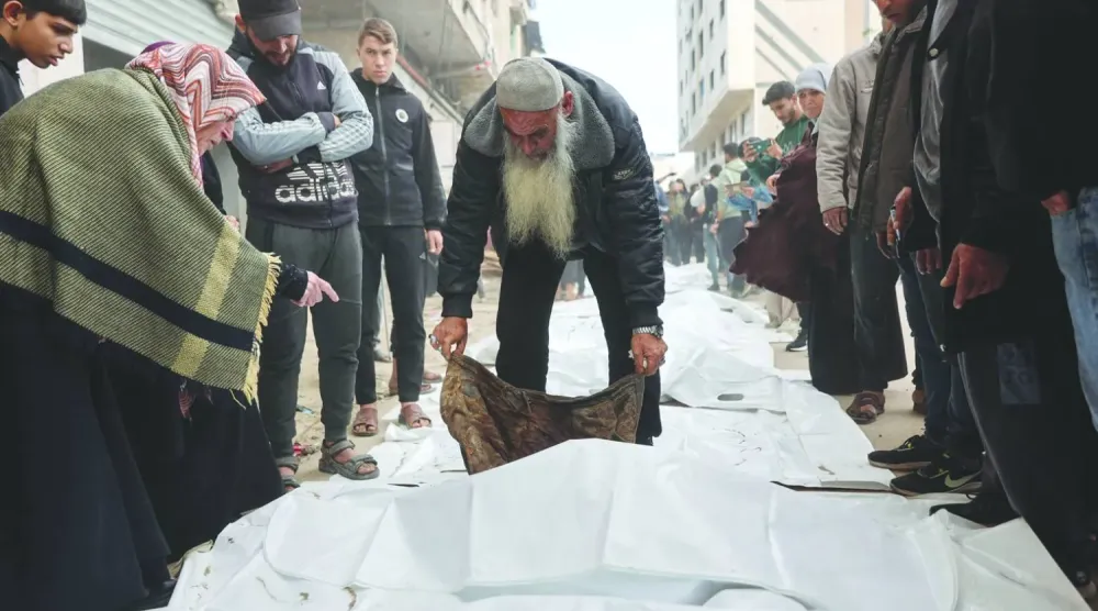 Gazze şehrinin er-Rimal mahallesinde 2023 yılında yıkılan bir binanın enkazından çıkarılan cesetlerin kimliklerini tespit etmeye çalışan Filistinliler (AFP)