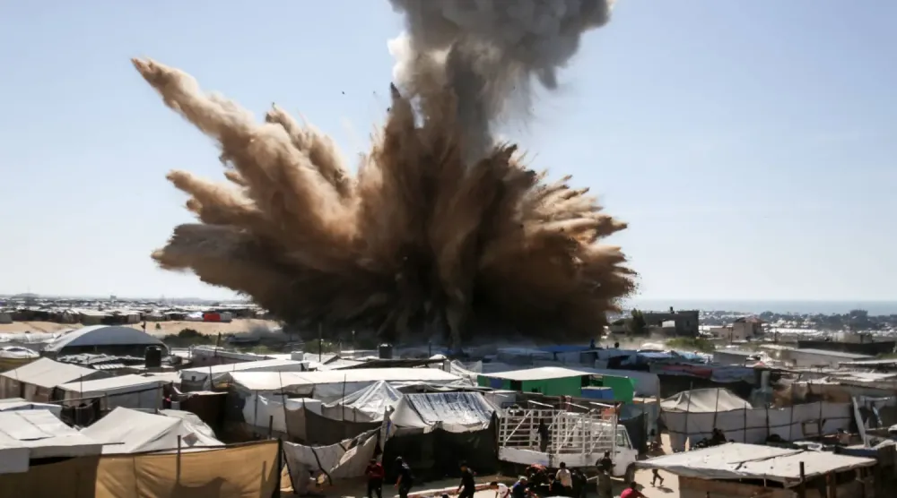 Han Yunus'un kuzeyindeki mülteci kampına düzenlenen saldırının ardından çadırların üzerinden duman yükselirken insanlar sığınacak yer arıyor. (AFP)