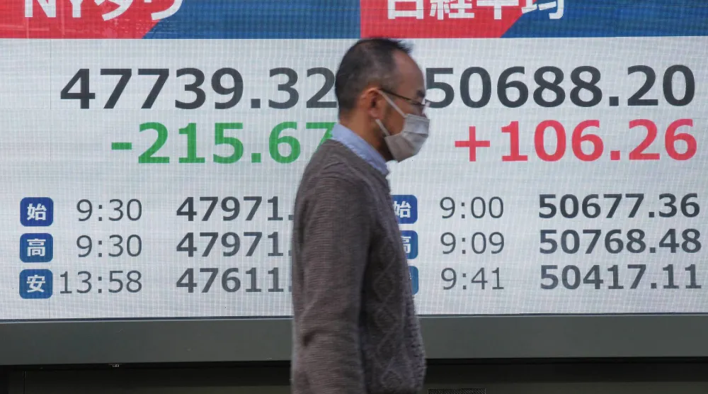 رجل يمر أمام لوحة إلكترونية تعرض حركة الأسهم وسط العاصمة اليابانية طوكيو (أ.ب)