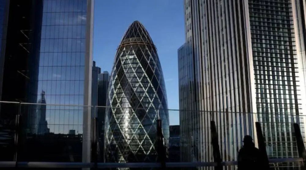 شخص ينظر من حديقة على سطح مبنى في منطقة الأعمال بمدينة لندن (رويترز)