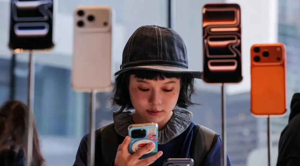 امرأة تستخدم جوالها داخل متجر لشركة «أبل» في بكين (رويترز)