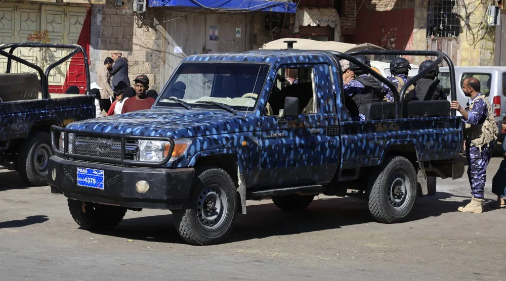 مسلحون حوثيون على متن عربة أمنية في أحد شوارع العاصمة اليمنية المختطفة صنعاء (إ.ب.أ)