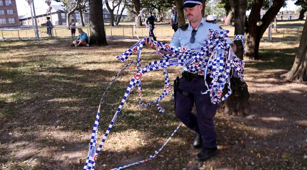 Police officers remove police tape from the scene of Sunday's shooting at Bondi Beach, in Sydney on December 17, 2025. (AFP)
