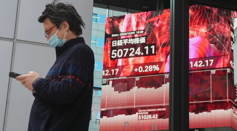 رجل يمر أمام شاشة تعرض حركة الأسهم في وسط العاصمة اليابانية طوكيو (أ.ب)