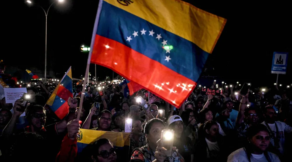 أنصار الرئيس الفنزويلي نيكولاس مادورو يلوّحون بالعلم الفنزويلي خلال مسيرة للمطالبة بالسلام في كاراكاس في 15 ديسمبر 2025 (أ.ف.ب)