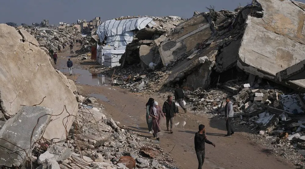  Palestinians walk along a street surrounded by buildings destroyed during Israeli air and ground operations in Gaza City, Wednesday, Dec. 17, 2025. (AP) 
