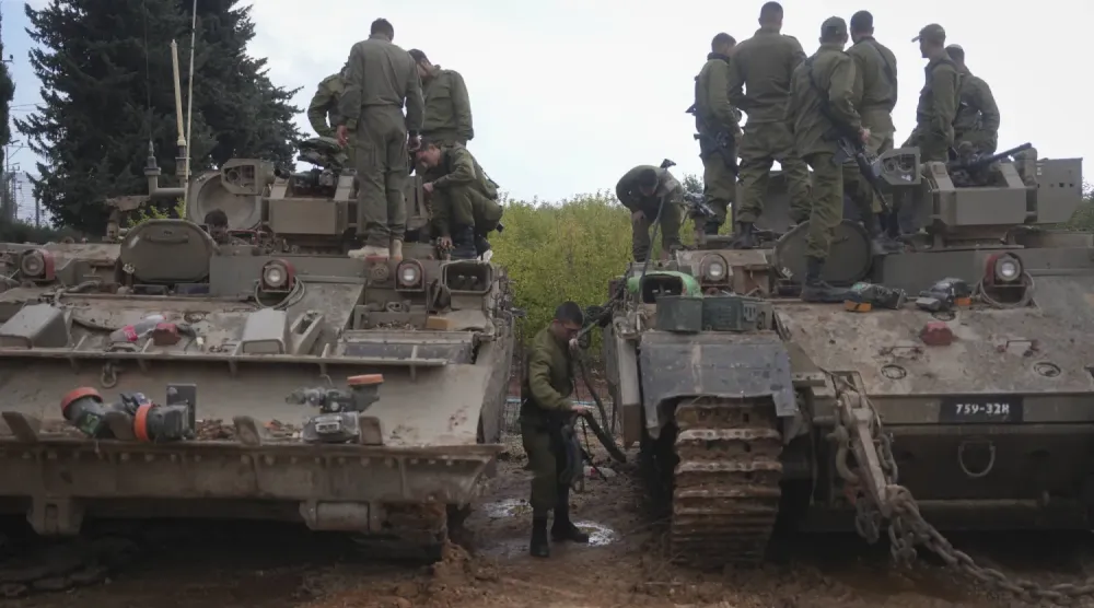 Yukarı Celile'deki Lübnan sınırına yakın Avivim tarım yerleşiminin dışında zırhlı askeri araçların üzerinde oturan İsrail askerleri, 28 Kasım 2024 (AP)