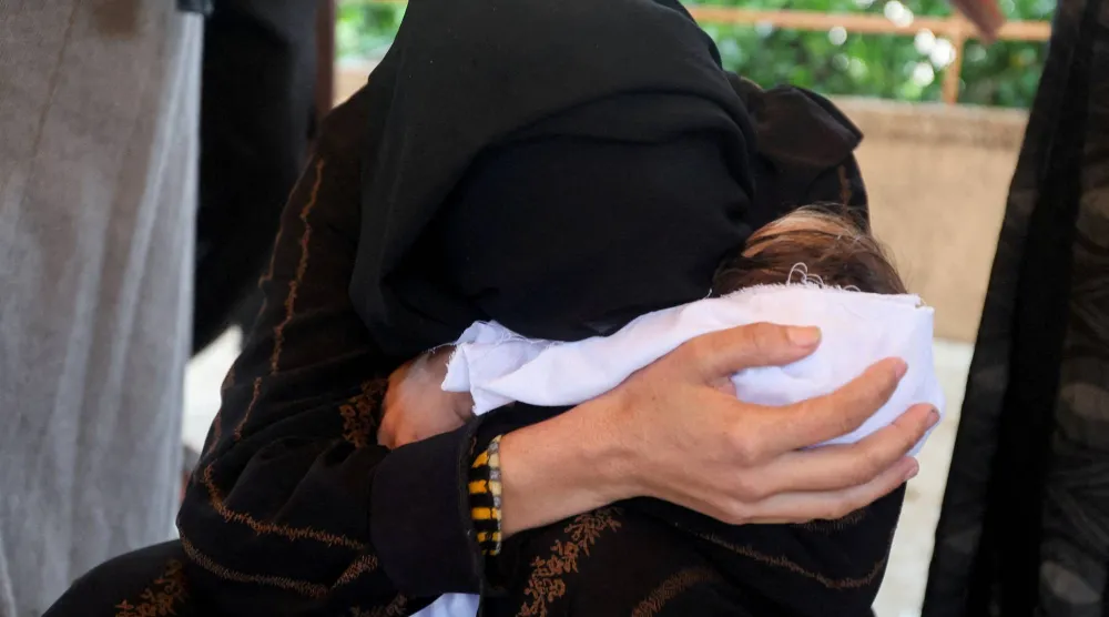 أم فلسطينية تودع ابنتها الرضيعة التي توفيت الأسبوع الماضي من البرد في مخيم بخان يونس بجنوب قطاع غزة (رويترز)