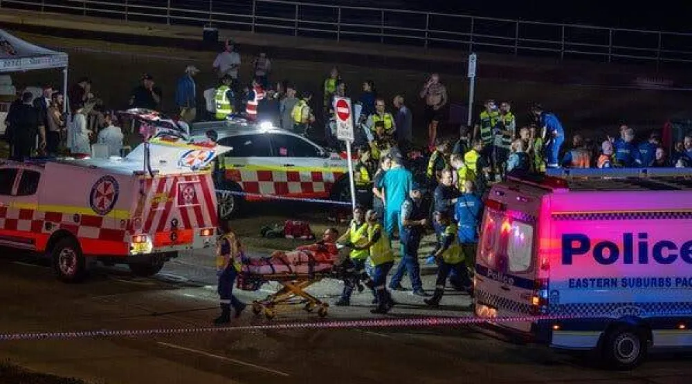 ينقل المسعفون رجلاً مصاباً على نقالة من موقع حادث إطلاق النار الجماعي في سيدني يوم الأحد (نيويورك تايمز)