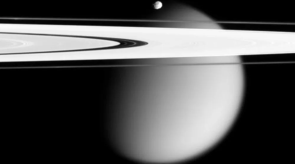This image made by the Cassini spacecraft and provided by NASA on March 12, 2006, shows two of Saturn's moons, the small Epimetheus and smog-enshrouded Titan, with Saturn's A and F rings stretching across the frame. (NASA via AP)