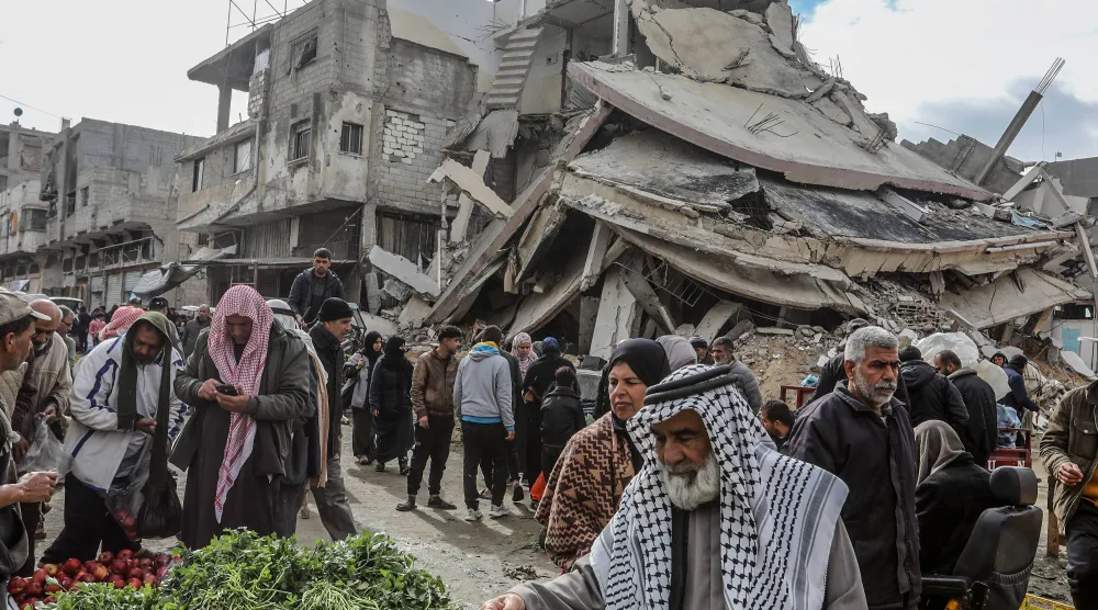 فلسطينيون يتسوقون وسط الدمار في خان يونس بجنوب قطاع غزة فبراير الماضي (د.ب.أ)