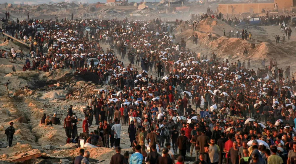 فلسطينيون يسيرون حاملين أكياس طحين على طول شارع الرشيد في غرب جباليا 17 يونيو 2025 بعد أن دخلت شاحنات مساعدات إنسانية شمال قطاع غزة عبر معبر زيكيم الحدودي الذي تسيطر عليه إسرائيل (أ.ف.ب)