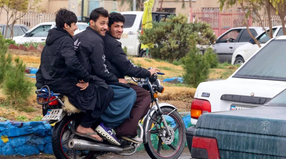 Baluch Iranian youths ride on a motorcycle in Zahedan, in the southeastern province of Sistan-Baluchistan bordering Afghanistan on December 18, 2025. (Photo by ATTA KENARE / AFP)