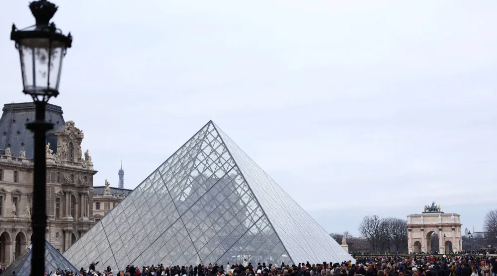 زوار يصطفون قرب الهرم الزجاجي لمتحف اللوفر للدخول (رويترز)