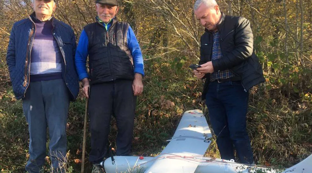 مجموعة من الأشخاص يقفون بجوار طائرة مسيرة يعتقد أنها روسية من نوع «أورلان - 10» سقطت في قوجه إيلي بشمال غرب تركيا (وكالة الأنباء التركية - أ.ف.ب)