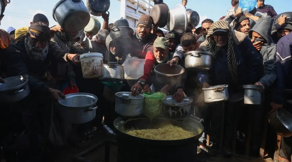 Displaced Palestinians gather to receive food rations at a charity kitchen in Khan Younis, southern Gaza (AFP)