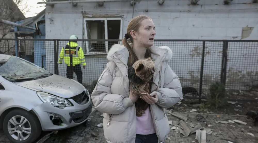 امرأة محلية برفقة كلبها تتفاعل مع موقع غارة روسية على مبنى خاص في زابوروجيا (إ.ب.أ)
