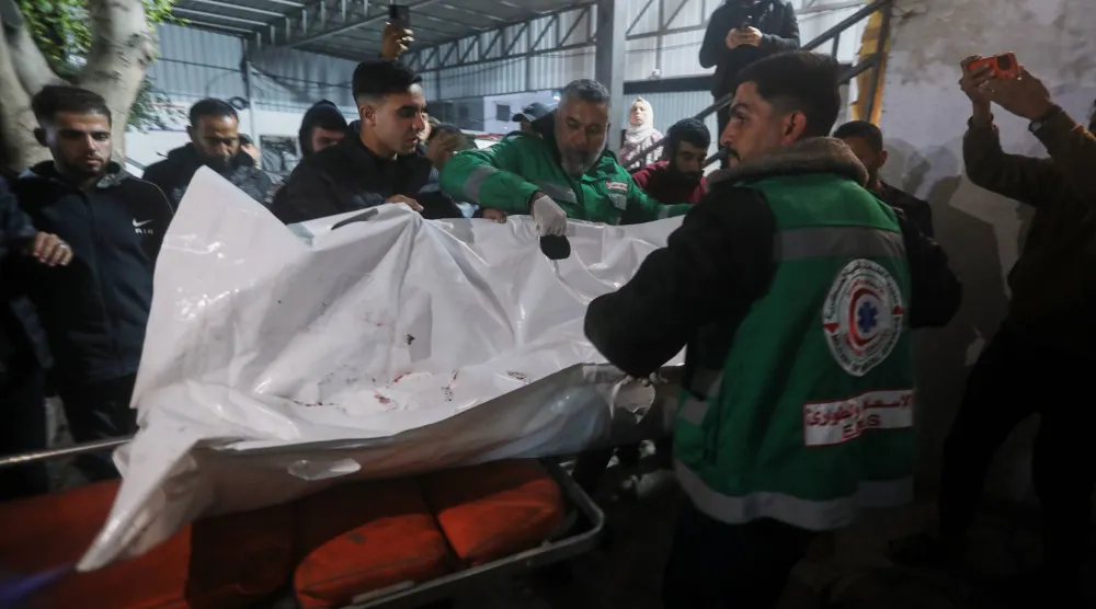 Palestinians carry the body of a person killed in an Israeli military strike as they arrive at Shifa Hospital in Gaza City, Friday, Dec. 19, 2025. (AP Photo/Yousef Al Zanoun)