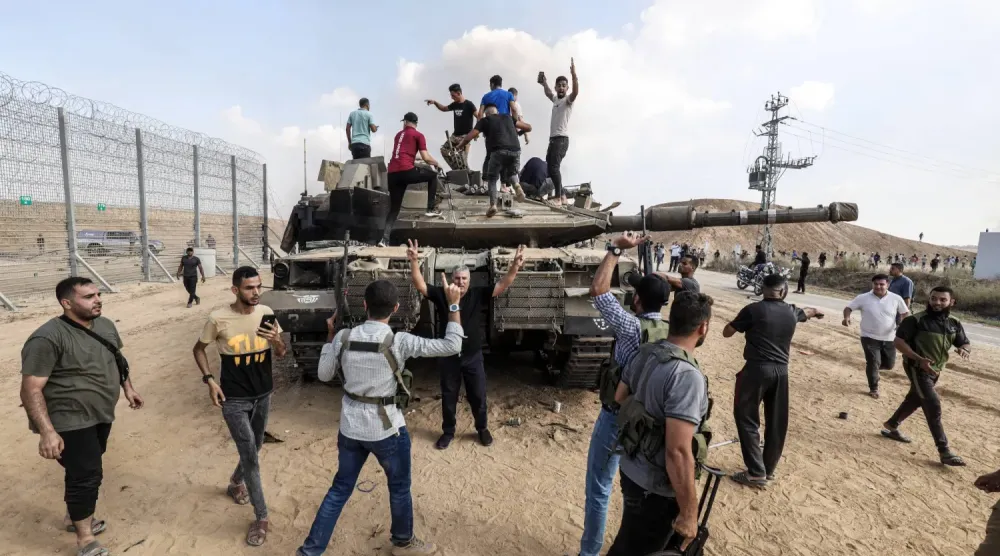 Han Yunus yakınlarında İzzeddin el-Kassam Tugayları tarafından ele geçirilen bir İsrail tankının üzerinde duran Filistinliler, 7 Ekim 2023 (DPA)