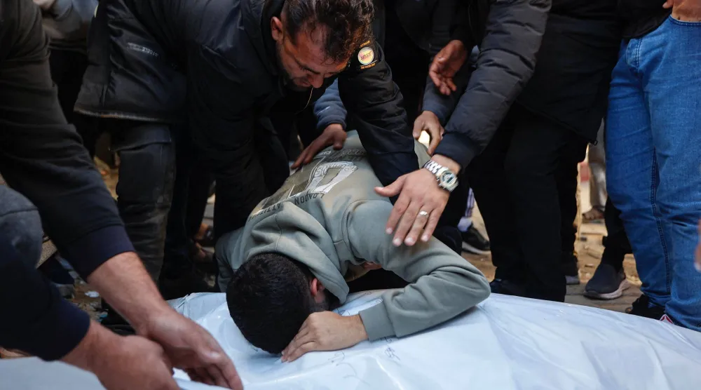 Bir akraba, Gazze şehrinin el-Tuffah mahallesinde sığınağa dönüştürülen okula düzenlenen İsrail bombardımanında bir gün önce hayatını kaybeden el-Nadir ailesi üyelerinin cenazeleri başında yas tutuyor (AFP)