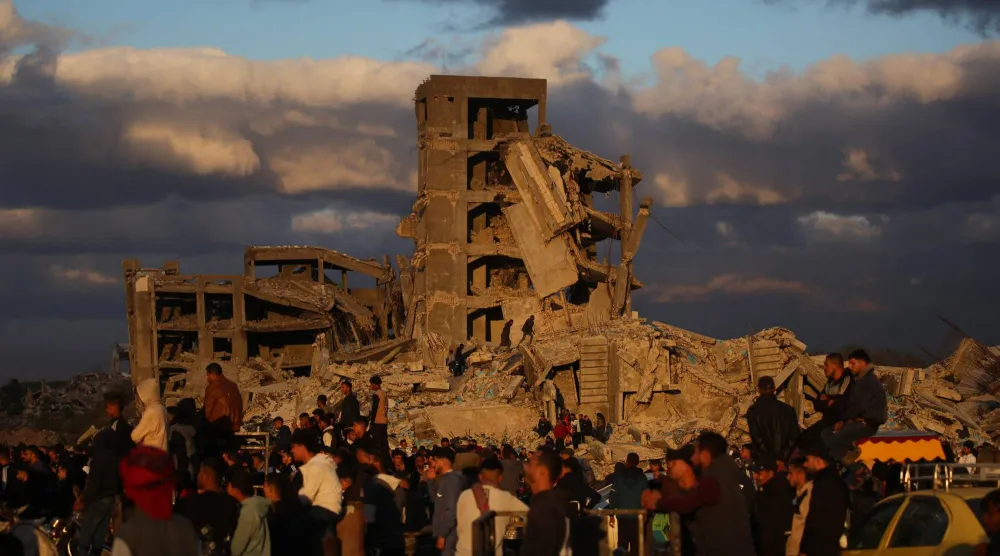 فلسطينيون قرب مبانٍ مدمرة في مخيم النصيرات بوسط قطاع غزة (أ.ف.ب)