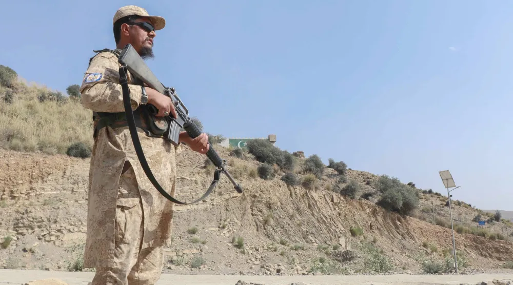 أحد عناصر أمن «طالبان» يقف حارساً على طريق قرب معبر غلام خان الحدودي بين أفغانستان وباكستان (أ.ف.ب)