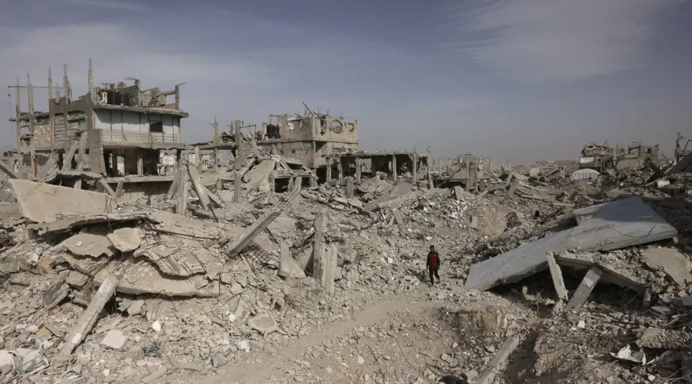 Gazze Şeridi'nin güneyindeki yıkılmış binaların enkazı arasında yürüyen Filistinli bir adam (AFP)