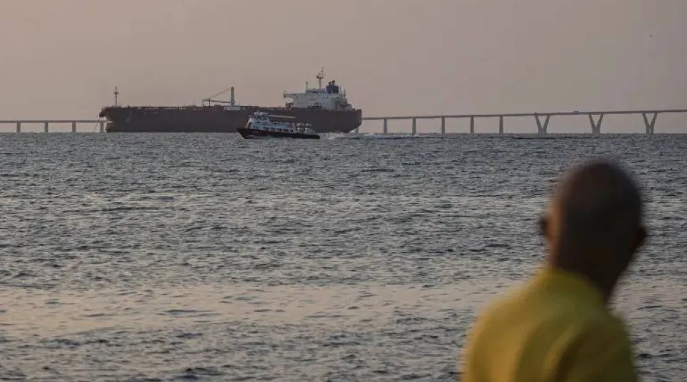 سفينة صغيرة تقترب من سفينة شحن كبيرة في عرض البحر (إ.ب.أ)