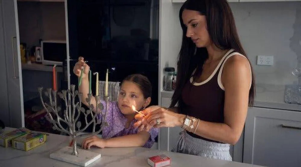 ريبيكا دي فيرولي مع ابنتها كلوي وهما تُجهّزان الشمعدان العائلي في منزلهما في نورث بونداي يوم الأحد (نيوريوك تايمز)