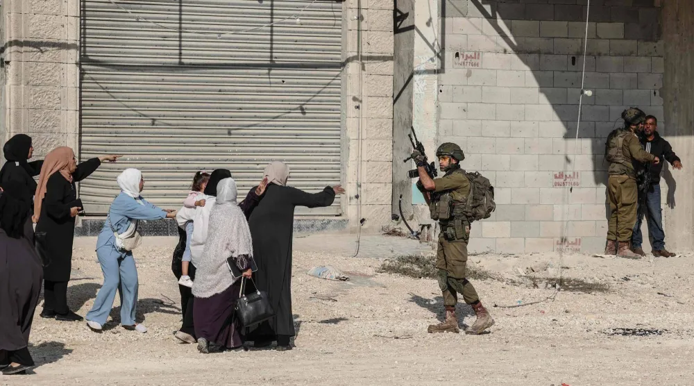 سيدات فلسطينيات أمام جنود إسرائيليين يعتقلون مواطنين في مخيم نور شمس بالضفة الغربية (أ.ف.ب)