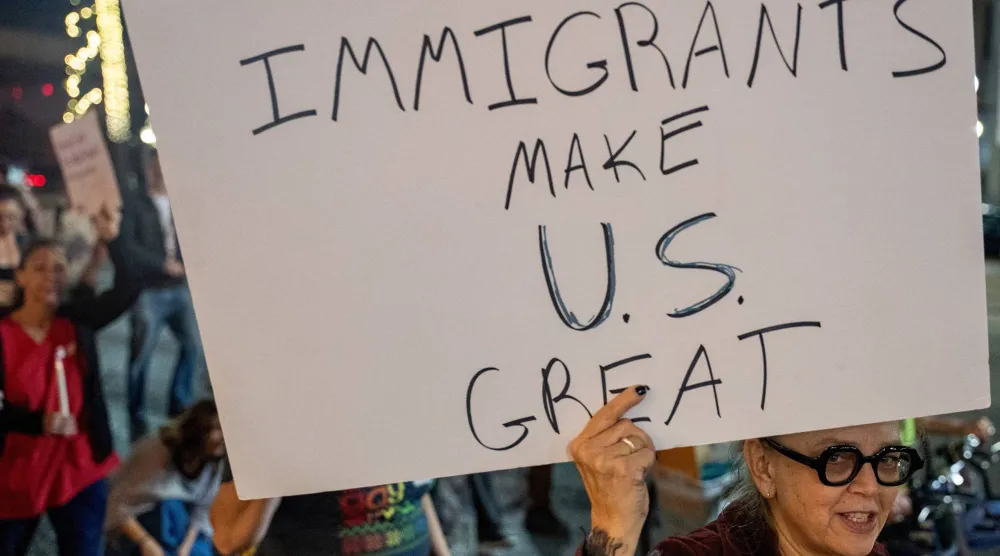 A woman holds a poster as immigrants rights activists stage a traditional Mexican posada, reenacting Mary and Joseph’s search for shelter, to symbolize immigrants seeking refuge from Immigration and Customs Enforcement (ICE) agents during the ongoing immigration operation "Catahoula Crunch", in New Orleans, Louisiana, US, December 18, 2025. REUTERS/Seth Herald